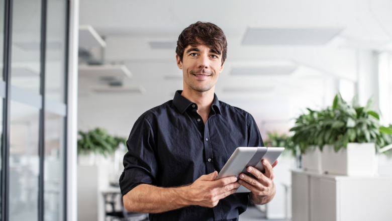 confident businessman holding digital tablet while standing in creative office low res 1