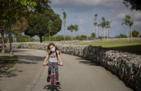 ep una nina con mascarilla monta en bicicleta por el parque en el tercer dia de desconfinamiento de