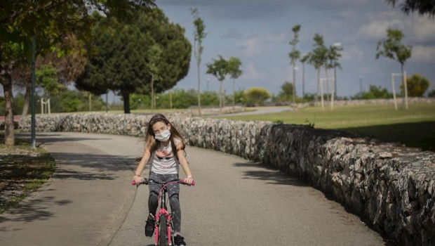 ep una nina con mascarilla monta en bicicleta por el parque en el tercer dia de desconfinamiento de