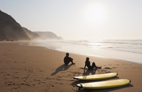 ep pareja de turistas descansando en una playa junto a unas tablas de surf