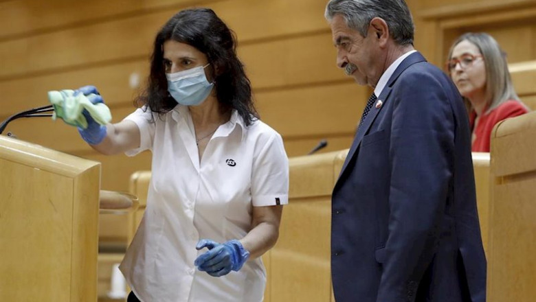ep una trabajadora limpia los microfonos de la tribuna junto al presidente de cantabria miguel angel
