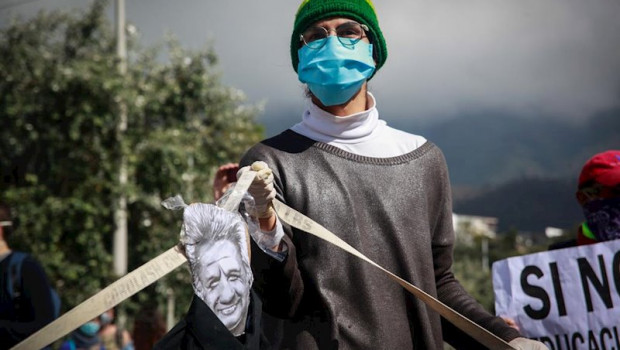 ep a man wearing a face mask and latex gloves holds a caricature image of ecuadorian president lenin