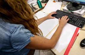 ep archivo   una mujer escribe en el teclado de su ordenador con papeles alrededor mientras trabaja