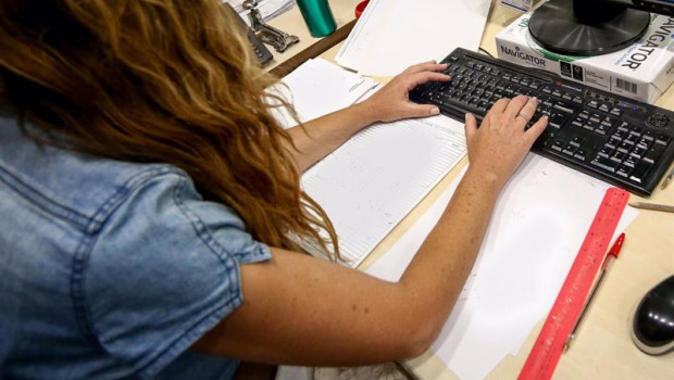ep archivo   una mujer escribe en el teclado de su ordenador con papeles alrededor mientras trabaja