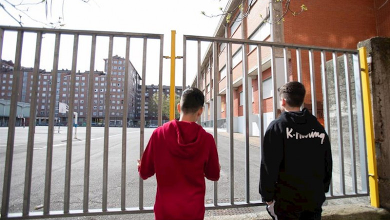 ep dos adolescentes observan el patio cerrado de un colegio durante el confinamiento por el estado