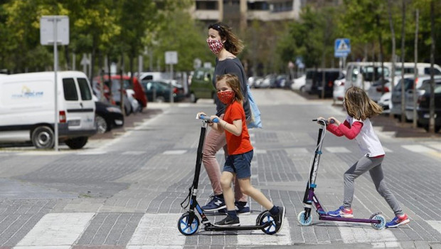 ep dos ninas con mascarillas cruzan un paso de cebra montadas en patinete tras salir a la calle el