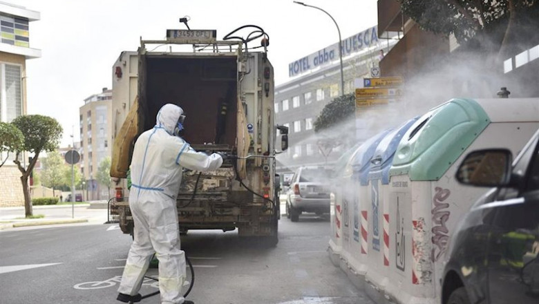 ep un trabajador protegido de cuerpo entero desinfecta los cubos de basura y de reciclaje en el