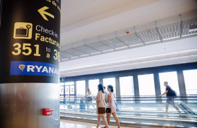 ep archivo   dos mujeres caminan al lado de un cartel indicativo de los mostradores de ryanair en el