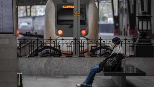 ep un hombre protegido con una mascarilla espera sentado en un banco en una estacion de tren de