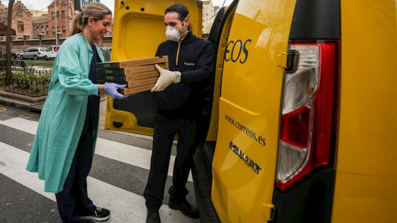 Una trabajadora sanitaria de la Clínica Ruber recoge las pizzas que le ha llevado un repartidor de Correos. | Ricardo Rubio - Europa Press ep una trabajadora sanitaria de la clinica ruber recoge las pizzas que le ha llevado un repartidor