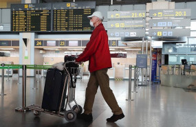 ep una persona con mascarilla anda con un carrito con su equipaje en el aeropuerto de valencia