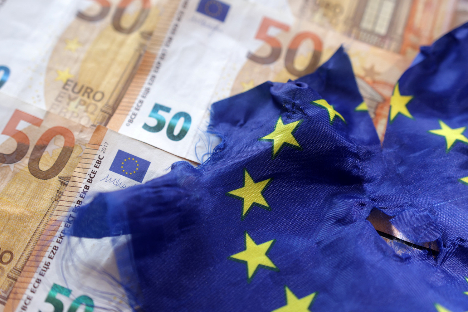 des billets de banque en euros et un drapeau europeen dechire 