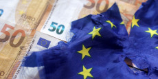 des billets de banque en euros et un drapeau europeen dechire 