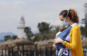 ep archivo   una mujer protegida con una mascarilla da un paseo con su bebe